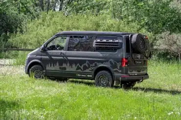 Wavecamper VW T6.1 LAST EDITION 4x4 Campervan mit Reserverad und Geländereifen auf einer Wiese im Wald