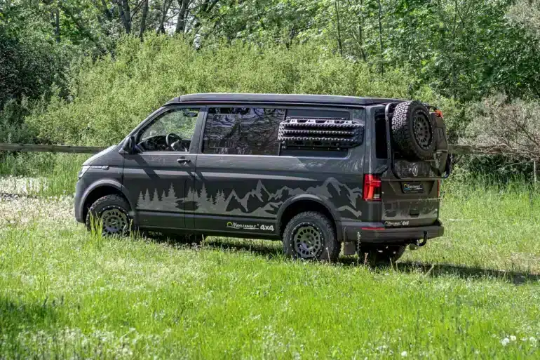 Wavecamper VW T6.1 LAST EDITION 4x4 Campervan mit Reserverad und Geländereifen auf einer Wiese im Wald