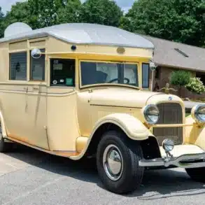 Cremefarbener 1927 Studebaker House Car mit verchromten Scheinwerfern und Wohnaufbau vor einem Wohnhaus