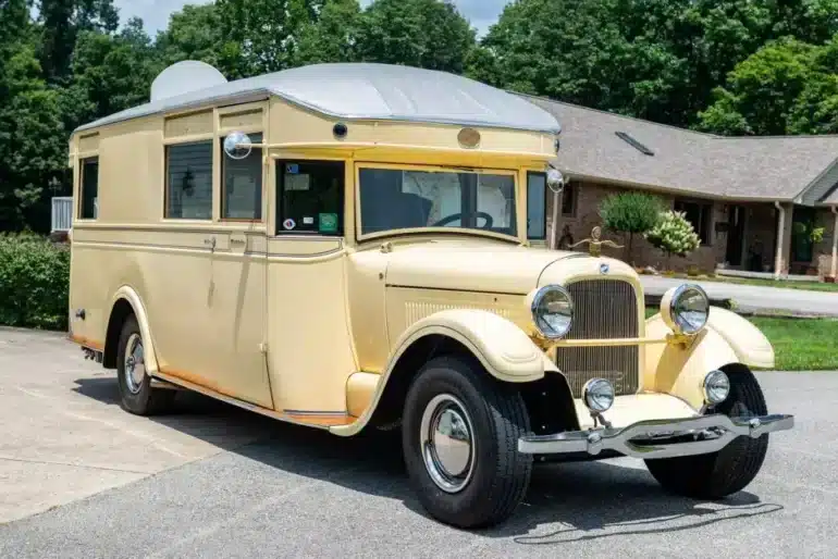 Cremefarbener 1927 Studebaker House Car mit verchromten Scheinwerfern und Wohnaufbau vor einem Wohnhaus