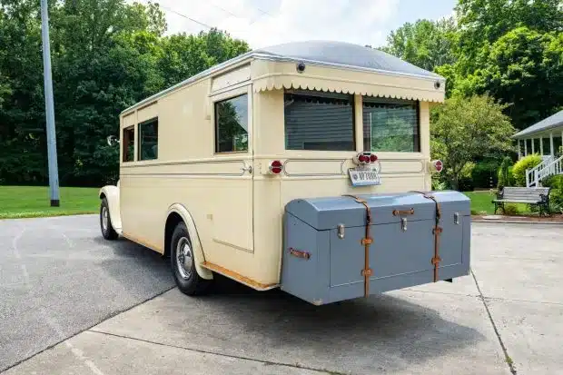 Heckansicht eines historischen Studebaker House Cars mit cremefarbener Karosserie, grauen Gepäckkisten und gewölbtem Dach
