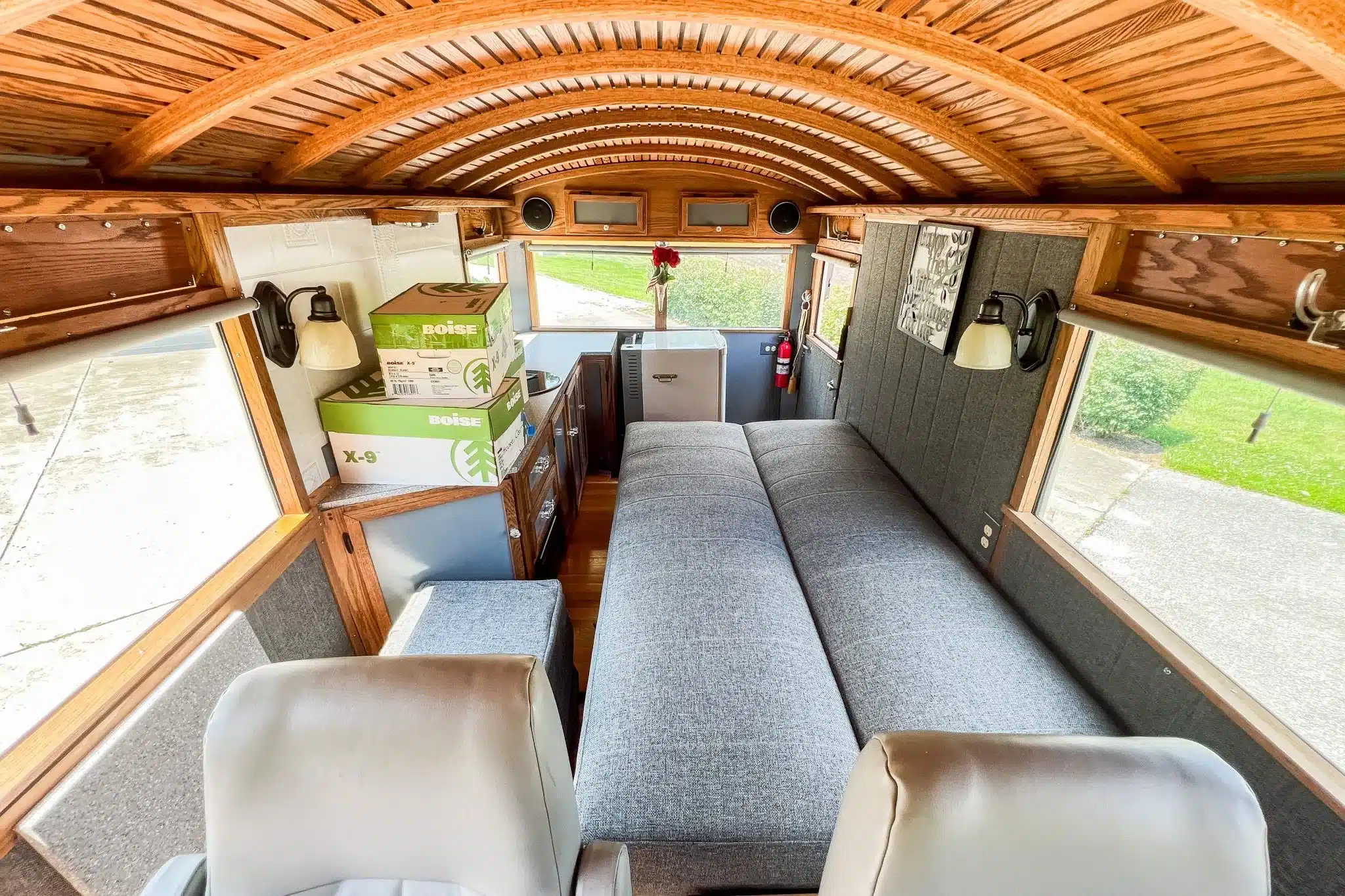 Innenraum des 1927 Studebaker House Car mit grauem Schlafsofa, Holzdecke und maßgefertigten Schränken