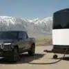 Aboard T4 Travel Trailer neben einem elektrischen Pickup in einer Berglandschaft