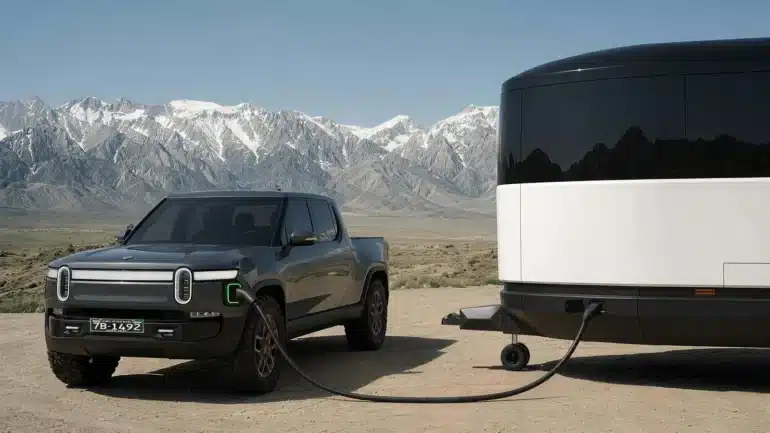 Aboard T4 Travel Trailer neben einem elektrischen Pickup in einer Berglandschaft