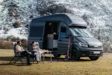 MAN TGE Campervan mit Allradantrieb vor verschneiten Bergen und geöffneter Schiebetür