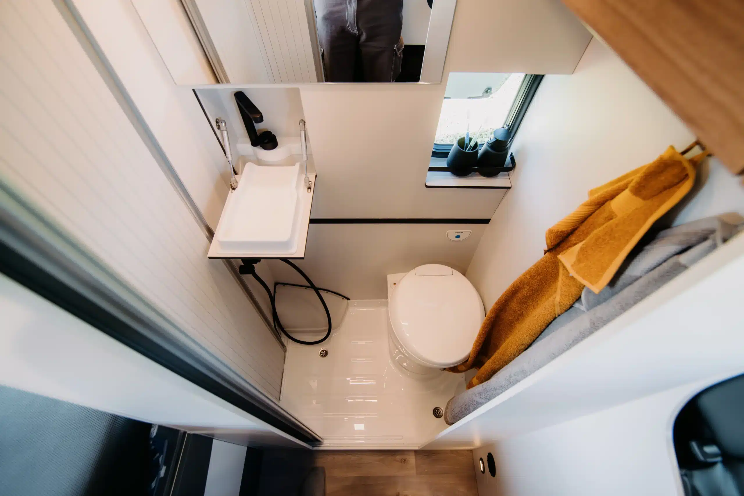 Badezimmer eines Campers mit Waschbecken, Dusche und Toilette
