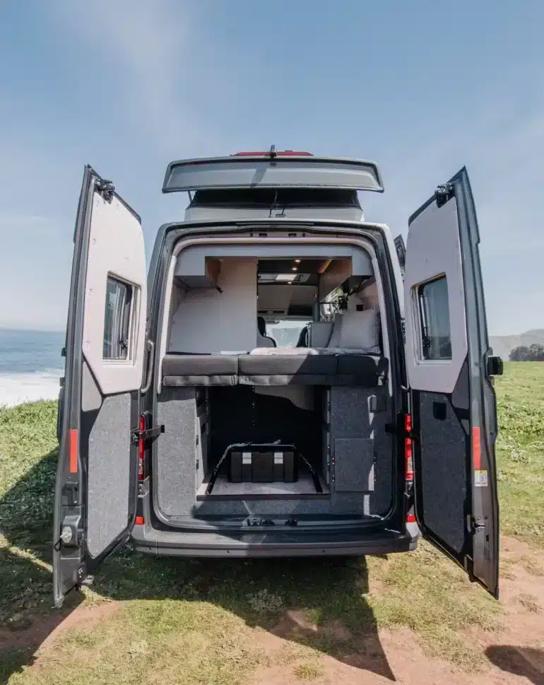 Heckansicht des ADVENTURE 6XR Campers mit geöffneten Türen, ausgeklapptem Hubdach und Schlafbereich