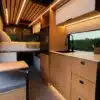 Innenraum des VANTRA Aire Campervans mit Küche, Spüle, Bambusmöbeln, Sitzbank und Bett