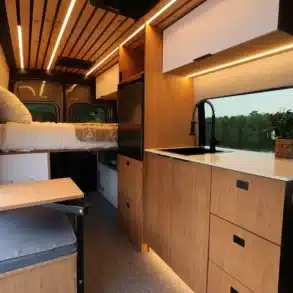 Innenraum des VANTRA Aire Campervans mit Küche, Spüle, Bambusmöbeln, Sitzbank und Bett