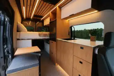 Innenraum des VANTRA Aire Campervans mit Küche, Spüle, Bambusmöbeln, Sitzbank und Bett