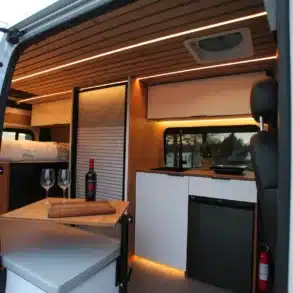 Innenraum des VANTRA Atlas Camper Vans mit Küche, Sitzbank, Bett, Holztisch und Zedernholzdecke