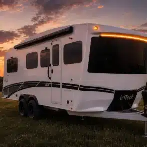 Weißer inTech Aucta Travel Trailer mit großer Panorama-Frontscheibe bei Sonnenuntergang