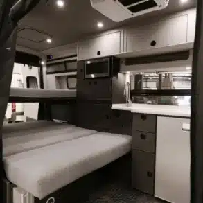 Innenraum eines ausgebauten Mercedes-Benz Sprinter Campervans mit Sitzbank, Küchenzeile, Mikrowelle und Oberschränken
