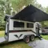 Black Wing 724-X Toy Hauler mit Heckrampe, Markise und Pick-up im Wald