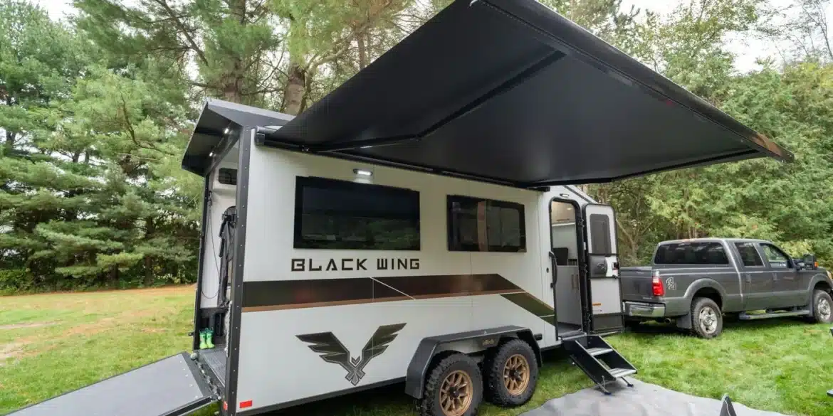 Black Wing 724-X Toy Hauler mit Heckrampe, Markise und Pick-up im Wald