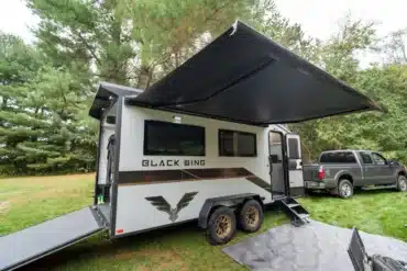 Black Wing 724-X Toy Hauler mit Heckrampe, Markise und Pick-up im Wald