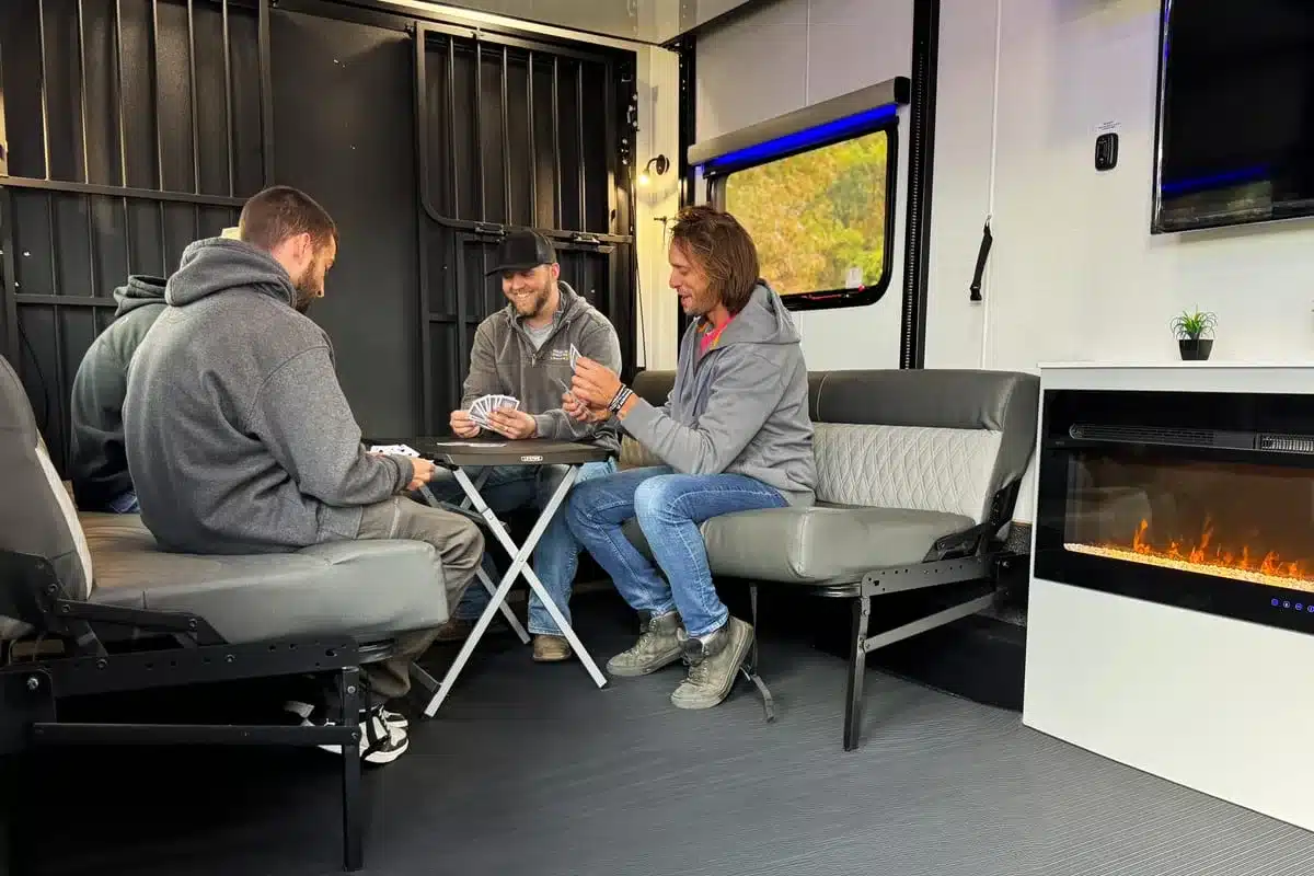 Innenraum des Black Wing 826-X Toy Haulers mit Sitzgruppen, Tisch, Fernseher und elektrischem Kamin