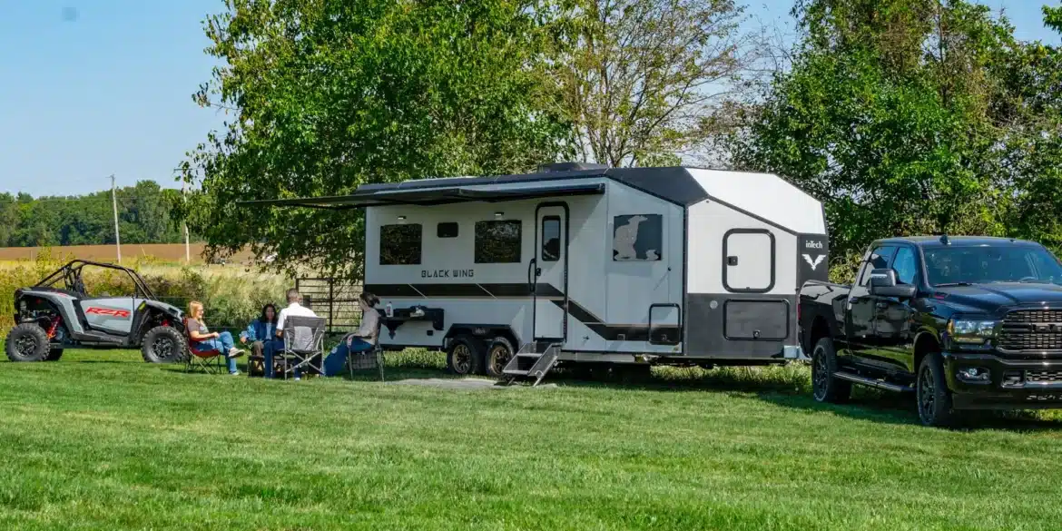 Black Wing 830-X Toy Hauler mit UTV und Pick-up auf einer Wiese