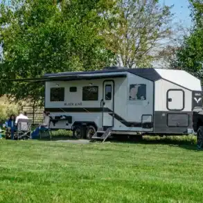 Black Wing 830-X Toy Hauler mit UTV und Pick-up auf einer Wiese