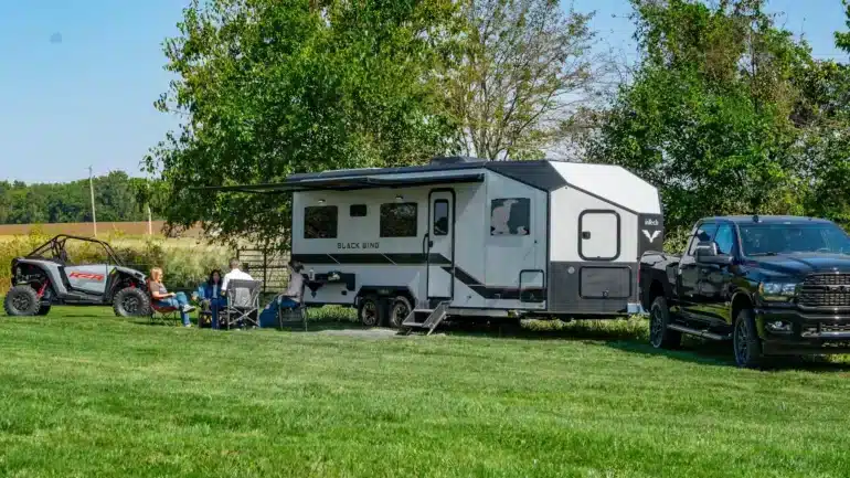 Black Wing 830-X Toy Hauler mit UTV und Pick-up auf einer Wiese