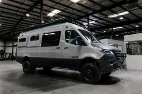 Weißer 4x4 Mercedes-Benz Sprinter-Camper von Field Van mit Offroad-Reifen, Frontstoßfänger, Dachträger und LED-Leuchten
