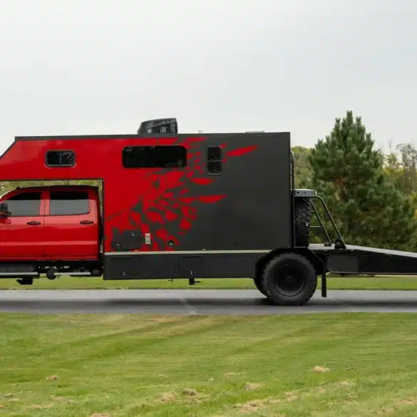 Seitenansicht eines rot-schwarzen Chevrolet Silverado 6500 Toter Home mit Wohnkabine und langem Heckdeck