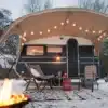 Schwarzer Constructam C190/B mit Vorzelt, Sitzmöbeln und Feuerstelle im Schnee
