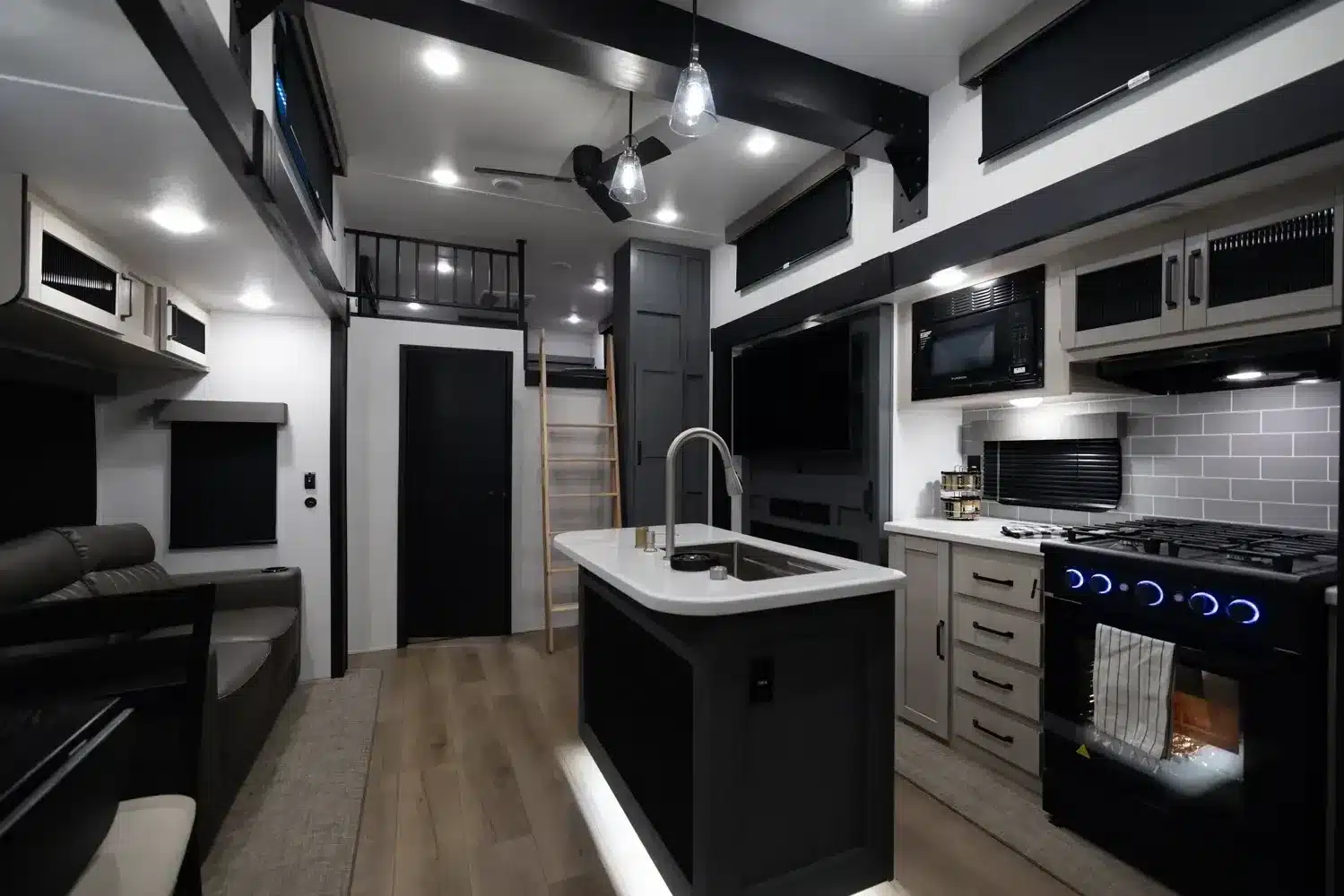 Innenraum eines Puma Vista Destination Trailers mit Küche, Wohnbereich, Fernseher, Kamin und Leiter zur Loft-Schlafebene
