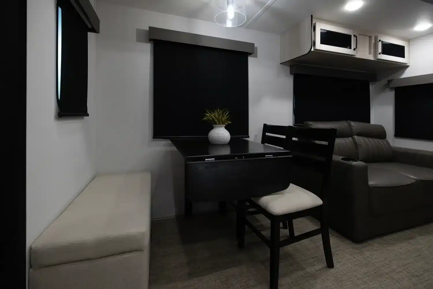 Innenraum eines Puma Vista Destination Trailers mit Essplatz, Sitzgruppe, Küchenmöbeln und verdunkelten Fenstern