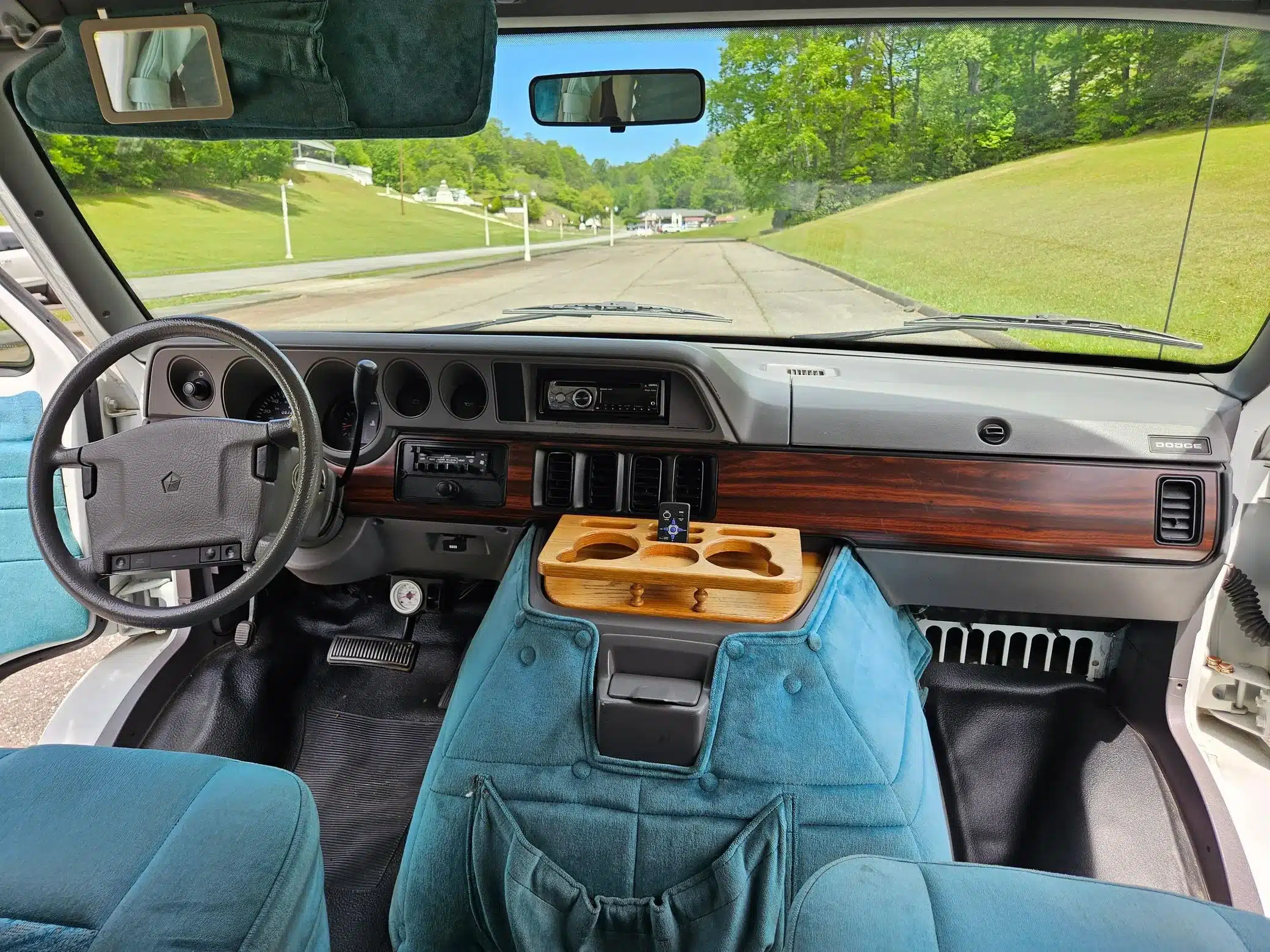 Innenraum eines 1995er Dodge Ram Van B350 Leisure Travel RV mit blauem Polster, Armaturenbrett und Holzmittelkonsole