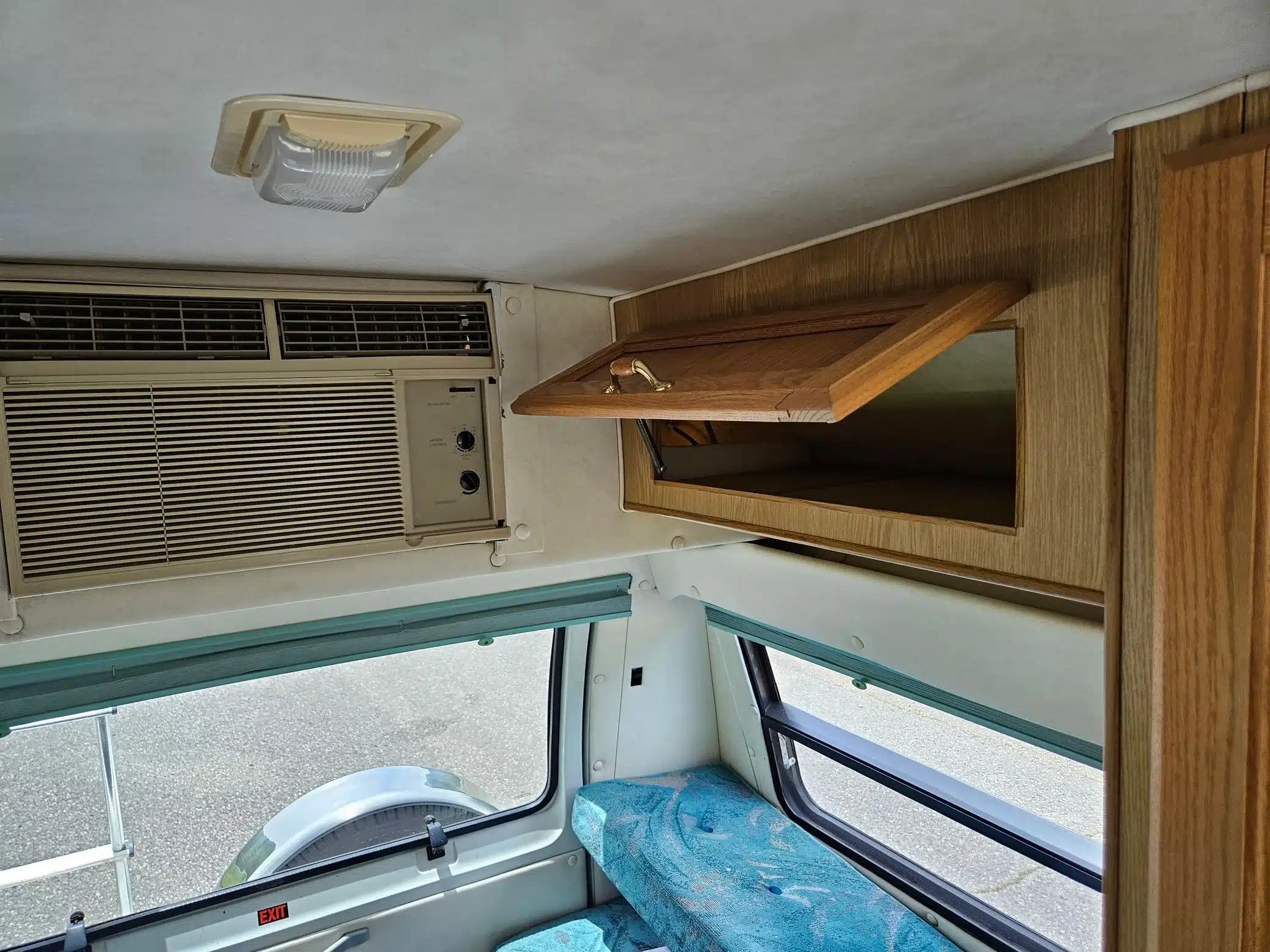 Innenraum eines Dodge Ram Van B350 Leisure Travel Reisemobils mit blauer Sitzbank, Holzschränken und Klimaanlage