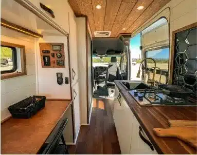 Innenraum des Papago Vans El Capitan mit Küche, Spülbecken, Induktionskochfeld und Holzverkleidung