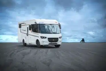 Weißes integriertes Eura Mobil Integra Line Reisemobil an einem Strand unter bewölktem Himmel