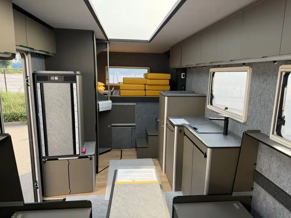 Innenansicht des elektrischen Wohnmobils CityFreighter × Vöhringer EVOLVE mit Küche, Sitzbereich und Oberschränken