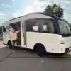 Weißes elektrisches EVOLVE-Wohnmobil mit geöffneter Seitentür und einer Person auf einem Parkplatz