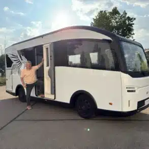 Weißes elektrisches EVOLVE-Wohnmobil mit geöffneter Seitentür und einer Person auf einem Parkplatz