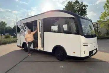Weißes elektrisches EVOLVE-Wohnmobil mit geöffneter Seitentür und einer Person auf einem Parkplatz