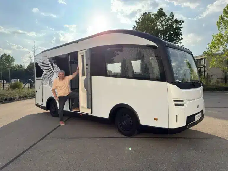 Weißes elektrisches EVOLVE-Wohnmobil mit geöffneter Seitentür und einer Person auf einem Parkplatz
