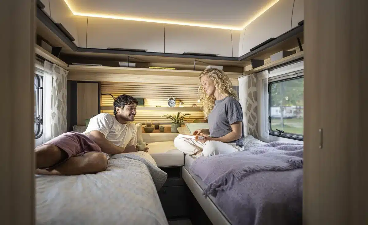 Innenraum eines Fendt-Caravan APERO mit zwei getrennten Betten, Sitzgruppe und zwei Personen
