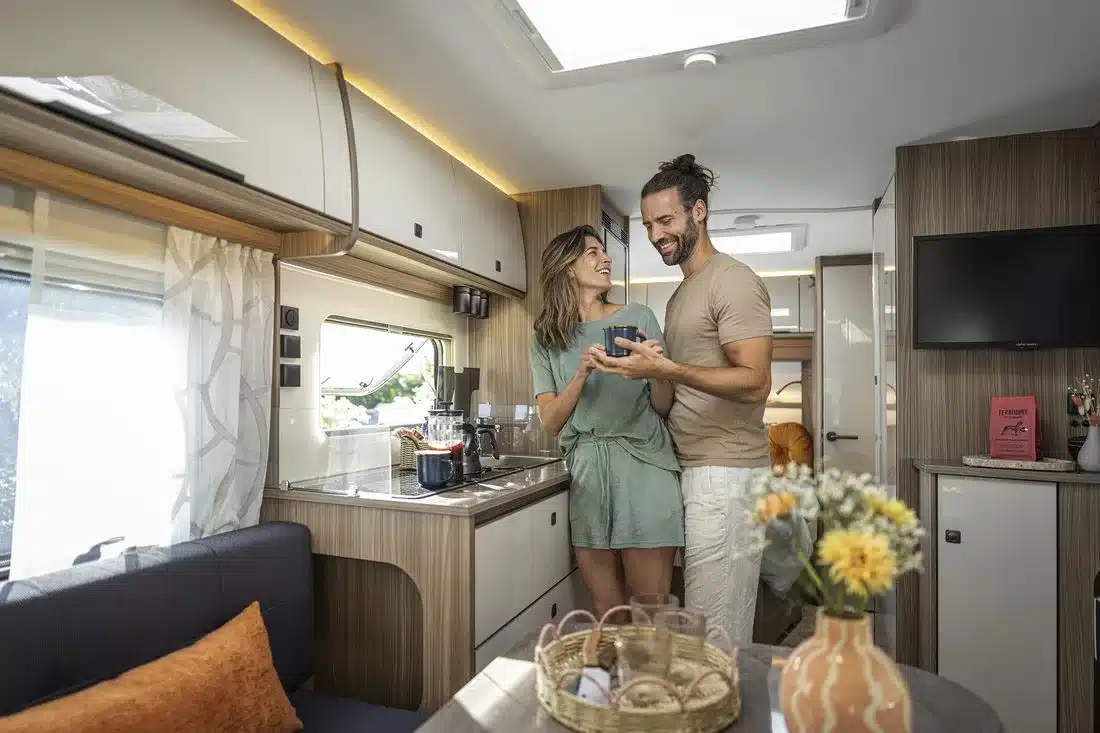 Heller Innenraum eines Fendt-Caravan TENDENZA mit Küche, Sitzgruppe und zwei Personen