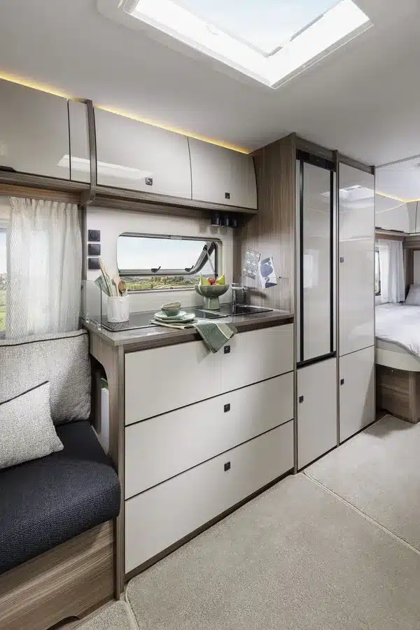 Innenraum eines Fendt-Caravan TENDENZA mit Küche, Sitzgruppe, Stauraummöbeln und Schlafbereich