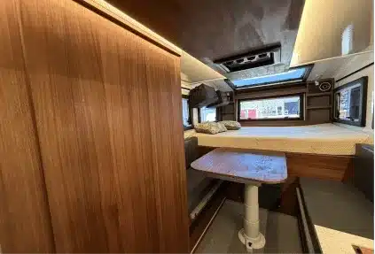 Innenraum des Field Adventure Vehicle mit Dinette, Holzausbau und Queensize-Bett