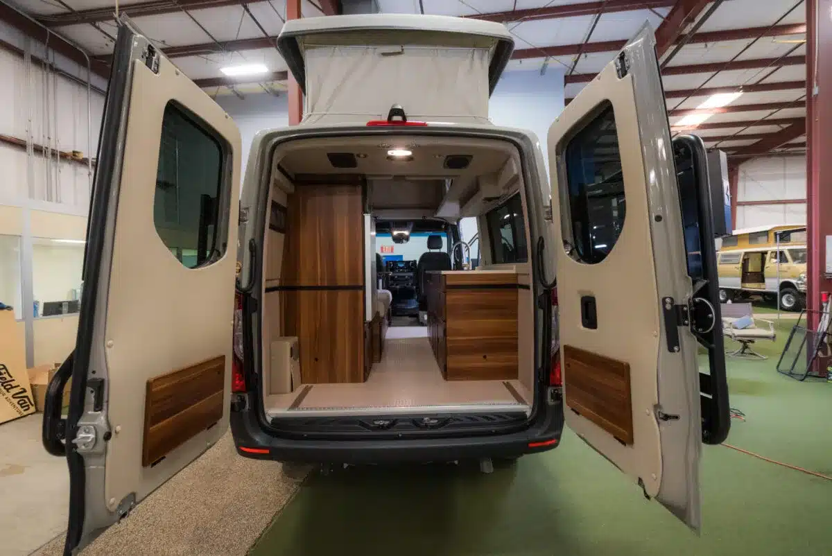 Innenansicht eines Field Van Campervans mit offenem Mittelgang, Holzküche und Stauraumschränken