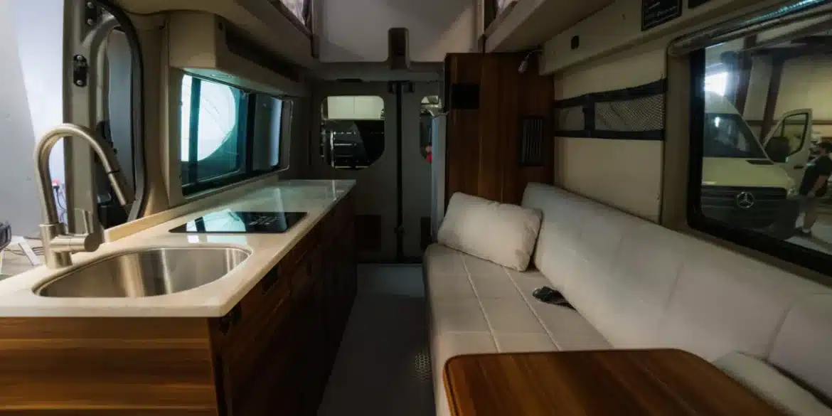 Innenraum eines Field Van Canyon Campervans mit Küchenzeile, Spüle, Sitzbank und Tisch