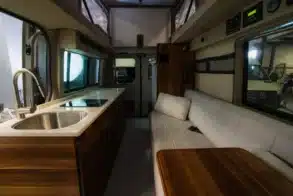Innenraum eines Field Van Canyon Campervans mit Küchenzeile, Spüle, Sitzbank und Tisch