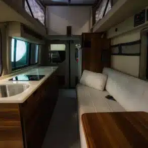 Innenraum eines Field Van Canyon Campervans mit Küchenzeile, Spüle, Sitzbank und Tisch