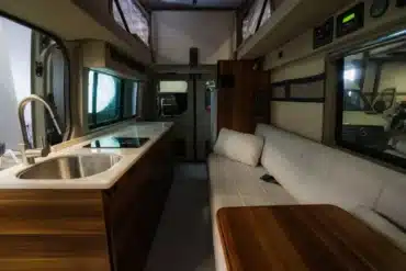 Innenraum eines Field Van Canyon Campervans mit Küchenzeile, Spüle, Sitzbank und Tisch