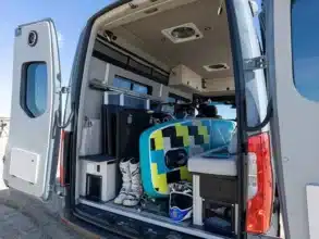 Geöffneter Campervan der Field Van Tide Series mit Surfboard, Skischuhen, Helmen und flexiblem Innenausbau
