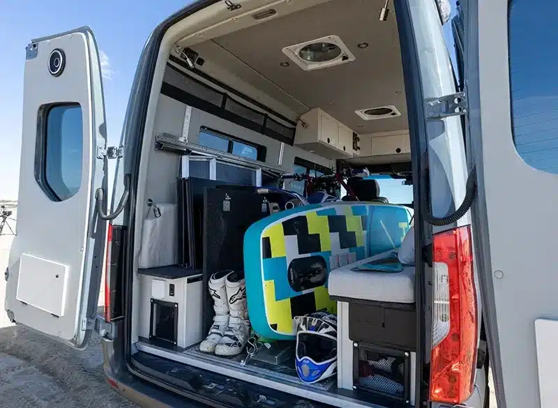 Geöffneter Campervan der Field Van Tide Series mit Surfboard, Skischuhen, Helmen und flexiblem Innenausbau