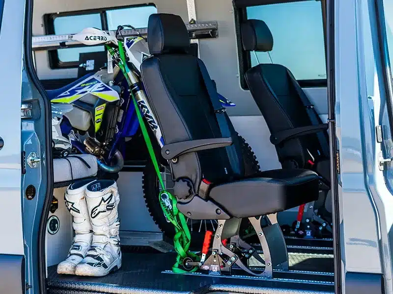 Innenraum eines Field Van Tide Campervans mit Dirtbike, Motorradstiefeln und herausnehmbaren Sitzen